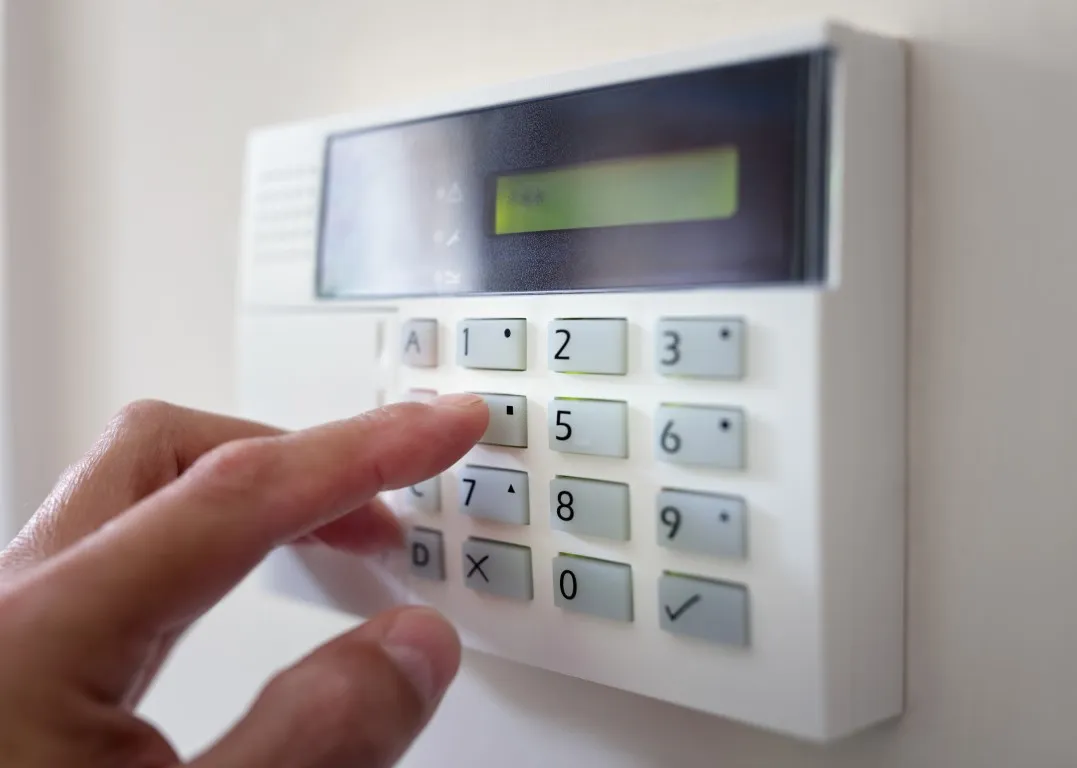 Hand gibt einen Code am Bedienteil einer Alarmanlage ein